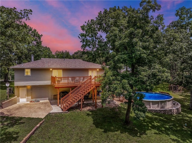 33383 Acorn Ln, Warsaw, MO 65355 - back of property at dusk featuring stairway, concrete driveway, a yard, an attached garage, and a deck