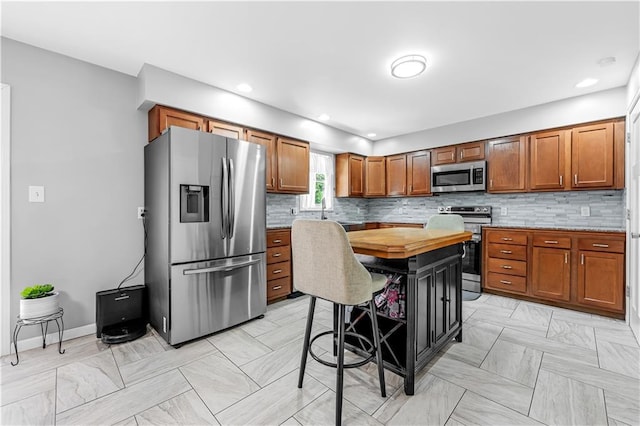 33383 Acorn Ln, Warsaw, MO 65355 - kitchen with stainless steel appliances, brown cabinetry, decorative backsplash, and recessed lighting