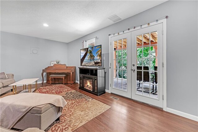 33383 Acorn Ln, Warsaw, MO 65355 - bedroom featuring access to outside, wood finished floors, french doors, a textured ceiling, and a glass covered fireplace
