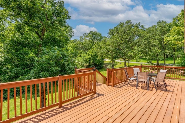 33383 Acorn Ln, Warsaw, MO 65355 - wooden deck with outdoor dining area, a lawn, and view of wooded area