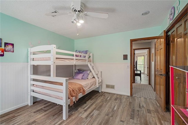 11530 Hemlock St, Overland Park, KS 66210 - bedroom featuring wood finished floors, wainscoting, a textured ceiling, and ceiling fan