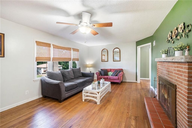 2110 N 70th Ter, Kansas City, KS 66109 - living room featuring ceiling fan, wood finished floors, a brick fireplace, and a textured ceiling