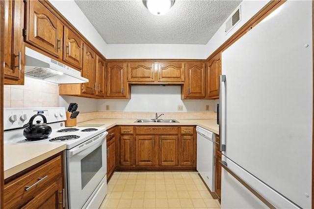 8001 Westridge Rd Unit 103, Raytown, MO 64138 - kitchen featuring white appliances, under cabinet range hood, brown cabinetry, a textured ceiling, and light countertops