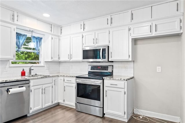 16722 E 35th Ter, Independence, MO 64055 - kitchen with stainless steel appliances, white cabinetry, light stone countertops, tasteful backsplash, and a textured ceiling