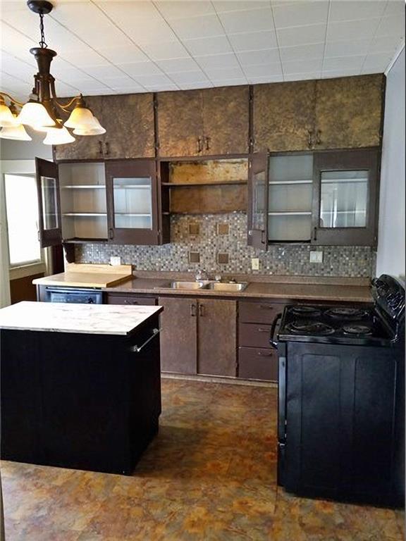 1918 S Elm St, Pittsburg, KS 66762 - kitchen with gas range oven, open shelves, tasteful backsplash, and pendant lighting