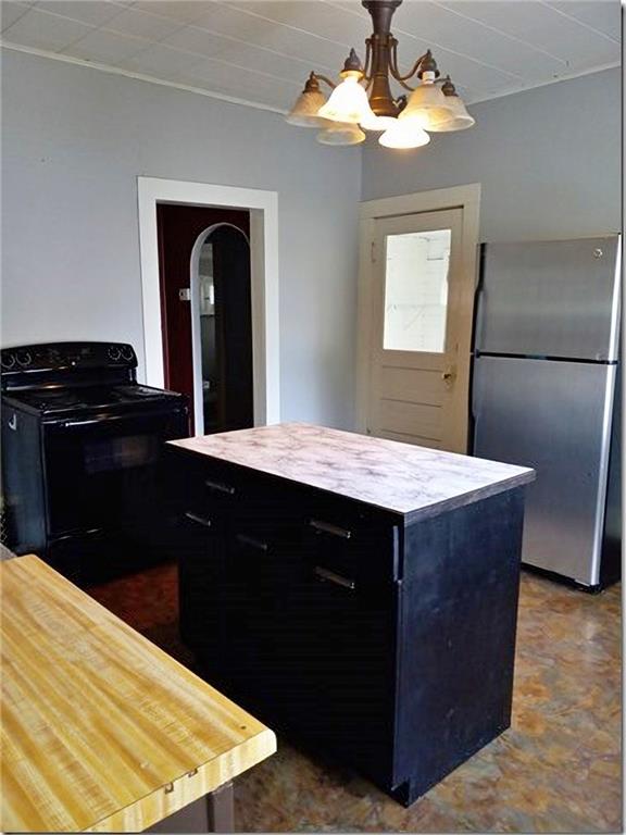 1918 S Elm St, Pittsburg, KS 66762 - kitchen featuring freestanding refrigerator, black electric range, dark cabinetry, light countertops, and arched walkways