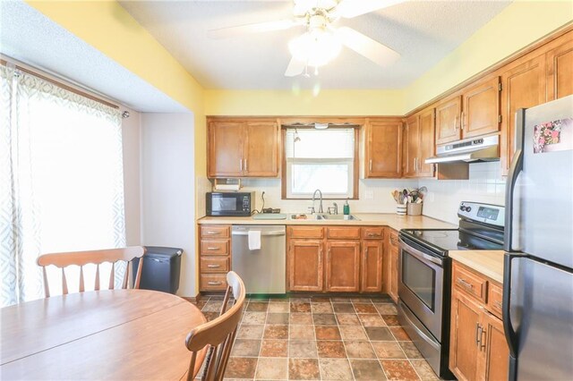 304 NE Independence Ave Unit B, Lees Summit, MO 64063 - kitchen featuring appliances with stainless steel finishes, under cabinet range hood, light countertops, stone finish floors, and ceiling fan