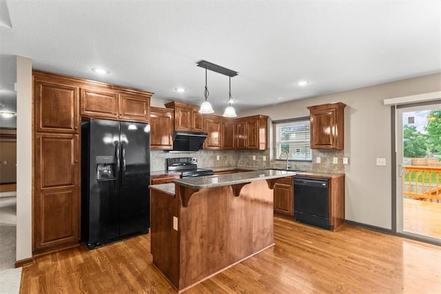 610 NW Green Dr, Grain Valley, MO 64029 - kitchen with black appliances, a kitchen bar, range hood, light wood-type flooring, and recessed lighting