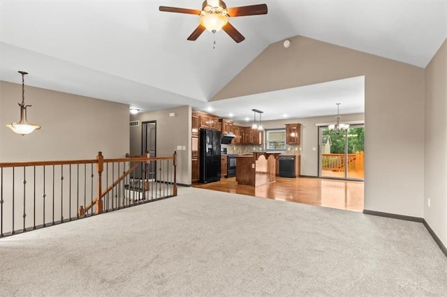610 NW Green Dr, Grain Valley, MO 64029 - unfurnished living room with a ceiling fan, light carpet, high vaulted ceiling, and a chandelier