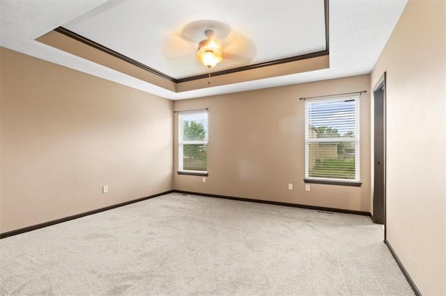 610 NW Green Dr, Grain Valley, MO 64029 - spare room featuring a raised ceiling, light carpet, a ceiling fan, and crown molding