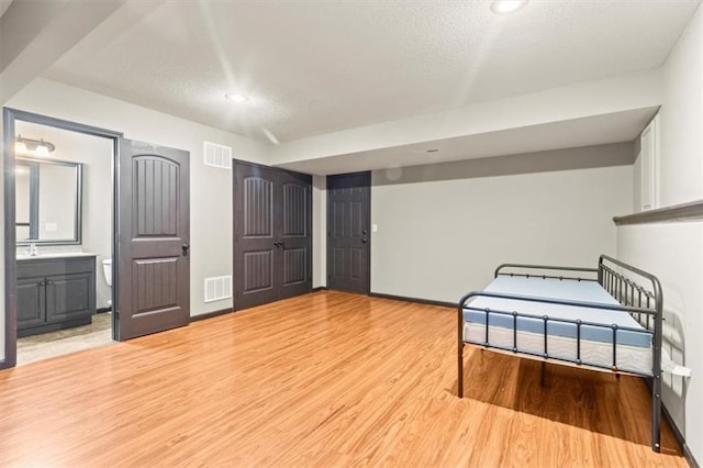 610 NW Green Dr, Grain Valley, MO 64029 - unfurnished bedroom featuring a textured ceiling, light wood-style flooring, ensuite bath, and recessed lighting