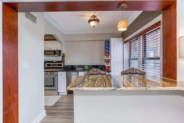 700 W 48th St Unit 301, Kansas City, MO 64112 - kitchen featuring stainless steel appliances, dark stone countertops, crown molding, white cabinetry, and wood finished floors