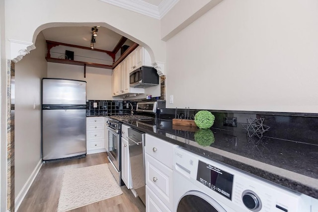 700 W 48th St Unit 301, Kansas City, MO 64112 - kitchen with stainless steel appliances, washer / clothes dryer, ornamental molding, arched walkways, and light wood-style flooring