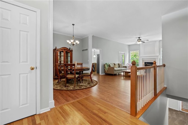 4116 NE 83rd St, Kansas City, MO 64119 - dining area featuring a ceiling fan, light wood-style flooring, a chandelier, a fireplace, and ornamental molding