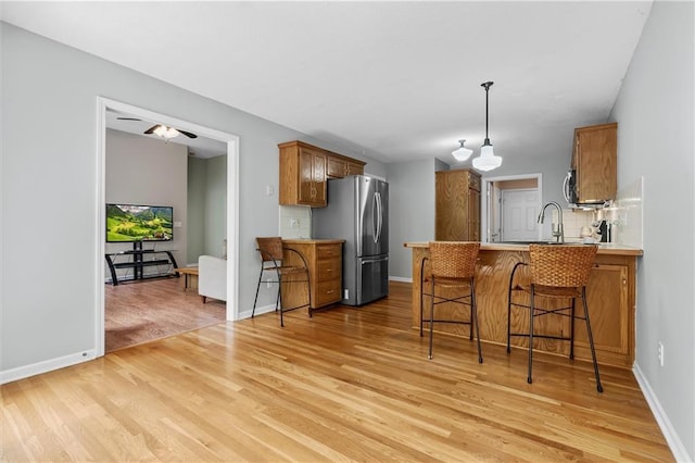 4116 NE 83rd St, Kansas City, MO 64119 - kitchen with appliances with stainless steel finishes, brown cabinetry, light wood-style flooring, and a peninsula