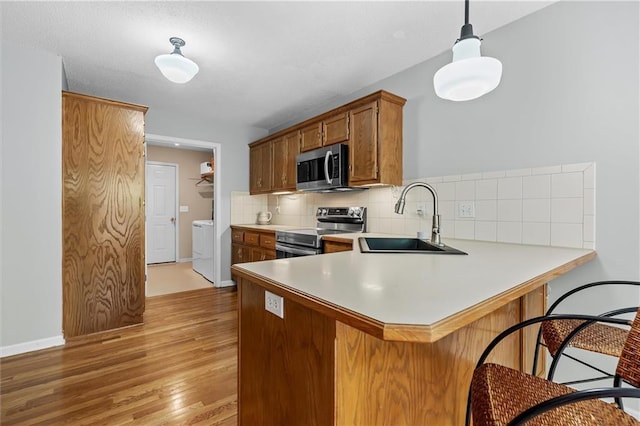 4116 NE 83rd St, Kansas City, MO 64119 - kitchen featuring appliances with stainless steel finishes, backsplash, light wood-type flooring, a breakfast bar, and light countertops