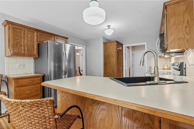 4116 NE 83rd St, Kansas City, MO 64119 - kitchen with stainless steel appliances, brown cabinetry, decorative backsplash, and a peninsula
