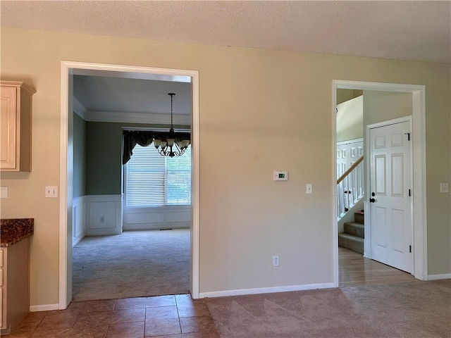 15598 S Blackfeather St, Olathe, KS 66062 - tiled empty room featuring carpet floors, a chandelier, stairway, and wainscoting
