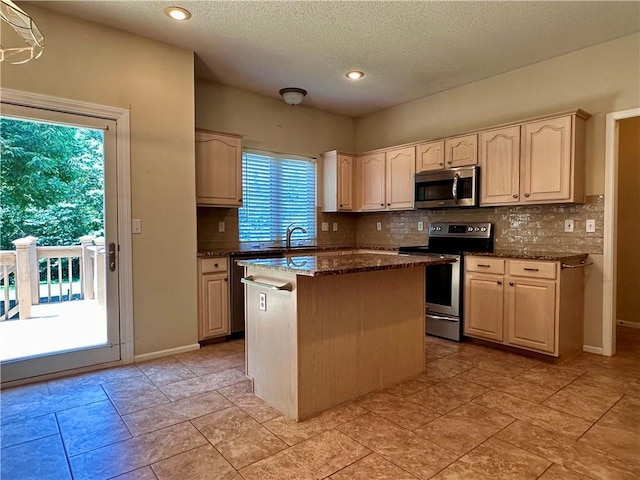 15598 S Blackfeather St, Olathe, KS 66062 - kitchen with appliances with stainless steel finishes, decorative backsplash, a kitchen island, dark stone countertops, and a textured ceiling