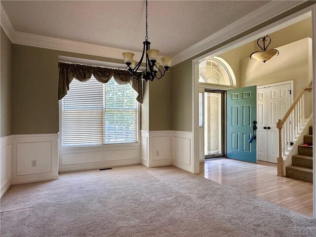 15598 S Blackfeather St, Olathe, KS 66062 - foyer with ornamental molding, carpet floors, a textured ceiling, a chandelier, and a wainscoted wall