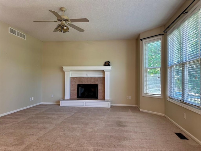 15598 S Blackfeather St, Olathe, KS 66062 - unfurnished living room featuring healthy amount of natural light, a ceiling fan, light carpet, a textured ceiling, and a tiled fireplace