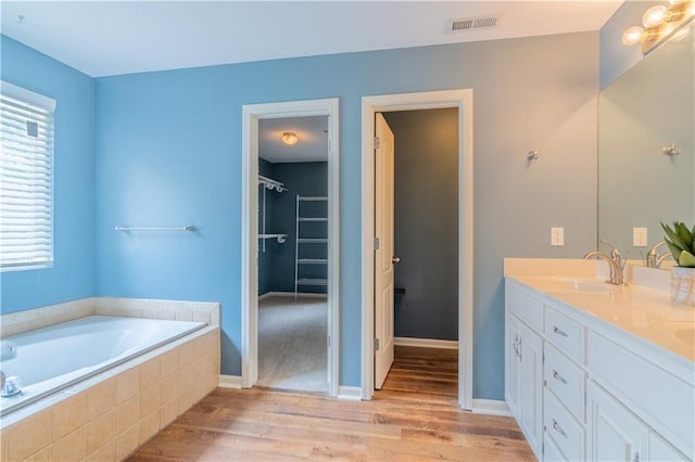 404 Wyndham Dr, Lansing, KS 66043 - full bathroom featuring wood finished floors, double vanity, and a bath
