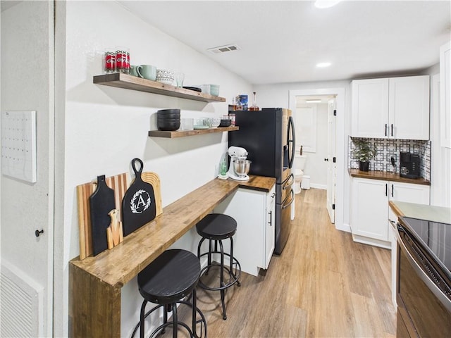 307 E 4th St, Holden, MO 64040 - kitchen featuring butcher block counters, stainless steel appliances, open shelves, light wood-style flooring, and white cabinets