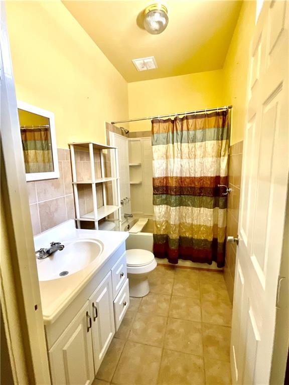 1870 N 27th St, Kansas City, KS 66104 - full bath featuring tile walls, vanity, shower / bath combination with curtain, tile patterned floors, and wainscoting