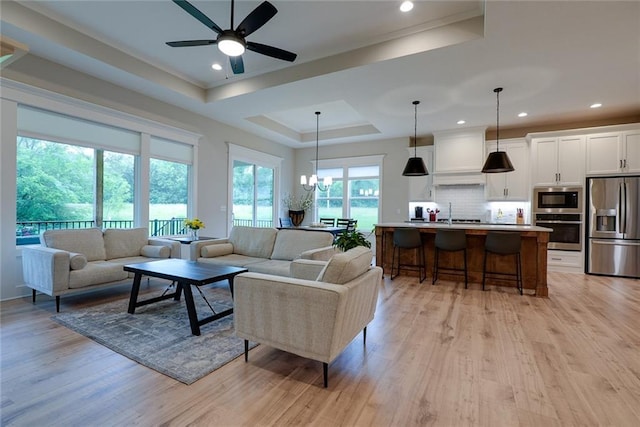 25411 W 142nd Pl, Olathe, KS 66061 - living area featuring light wood finished floors, a chandelier, ceiling fan, a tray ceiling, and recessed lighting
