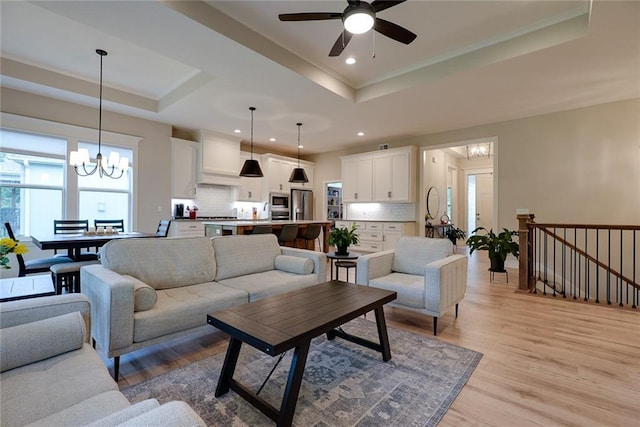 25411 W 142nd Pl, Olathe, KS 66061 - living room with a tray ceiling, a chandelier, a ceiling fan, light wood-style flooring, and recessed lighting