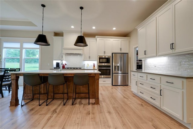 25411 W 142nd Pl, Olathe, KS 66061 - kitchen featuring stainless steel appliances, decorative backsplash, white cabinets, light wood-type flooring, and a breakfast bar area