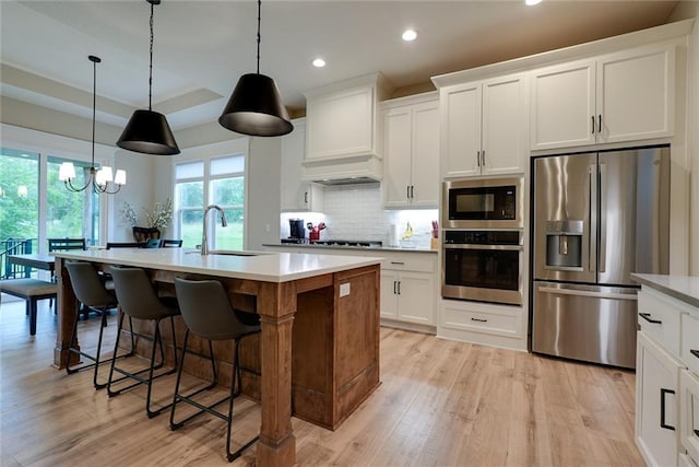 25411 W 142nd Pl, Olathe, KS 66061 - kitchen featuring stainless steel appliances, light wood-style flooring, recessed lighting, custom range hood, and light countertops