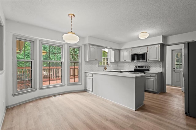9602 W 116th St, Overland Park, KS 66210 - kitchen featuring gray cabinetry, stainless steel appliances, a peninsula, tasteful backsplash, and a textured ceiling
