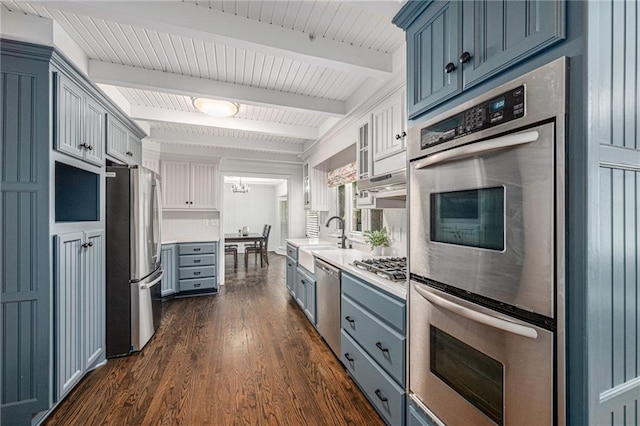 3818 W 52nd Ter, Roeland Park, KS 66205 - kitchen with stainless steel appliances, light countertops, dark wood-style flooring, beam ceiling, and blue cabinets