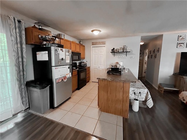 21 Oak Crest Dr, Linn Valley, KS 66040 - kitchen with black appliances, dark countertops, light wood-style floors, brown cabinetry, and a peninsula