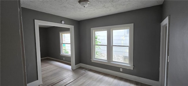 2524 Askew Ave, Kansas City, MO 64127 - spare room with healthy amount of natural light, wood finished floors, and a textured ceiling