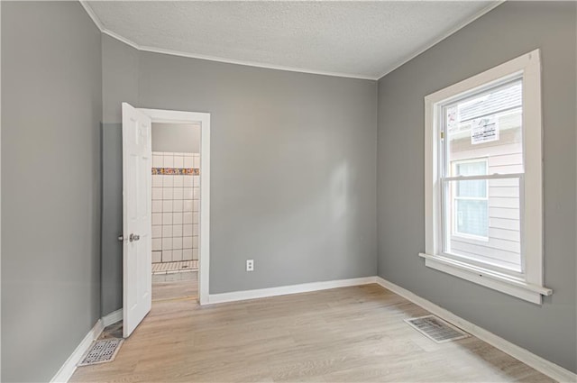 2524 Askew Ave, Kansas City, MO 64127 - unfurnished room featuring plenty of natural light, crown molding, light wood-style floors, and a textured ceiling