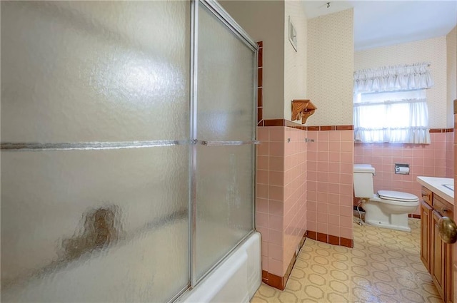 1933 N 83rd Ter, Kansas City, KS 66112 - bathroom with vanity, a wainscoted wall, tile walls, combined bath / shower with glass door, and tile patterned floors