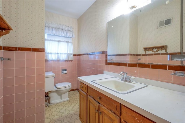 1933 N 83rd Ter, Kansas City, KS 66112 - bathroom with wallpapered walls, tile walls, vanity, and wainscoting