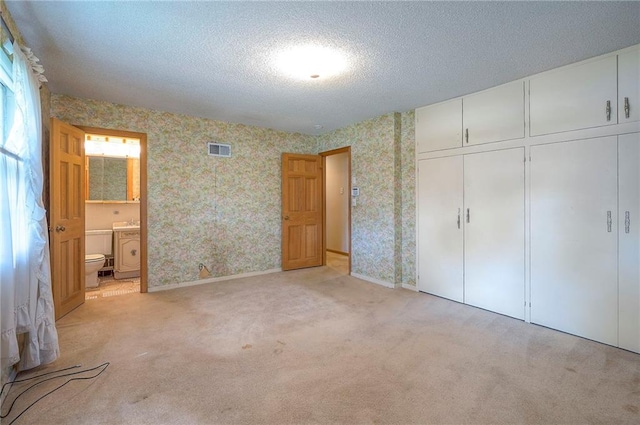 1933 N 83rd Ter, Kansas City, KS 66112 - unfurnished bedroom with wallpapered walls, a closet, light colored carpet, a textured ceiling, and ensuite bath