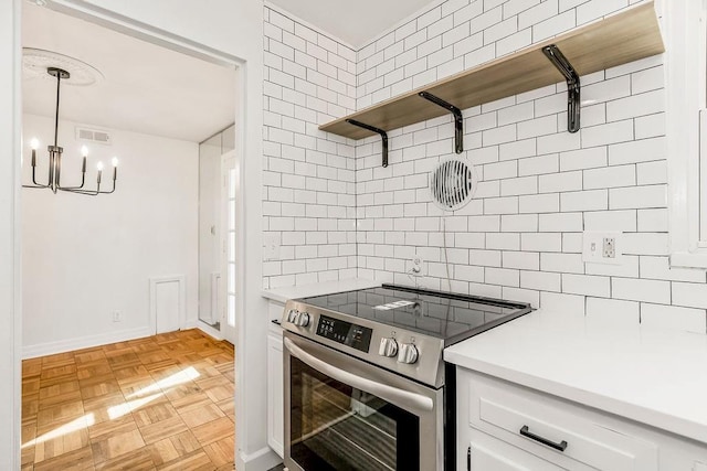4428 N Monroe Ave, Kansas City, MO 64117 - kitchen with stainless steel electric range oven, decorative backsplash, a chandelier, light countertops, and white cabinets