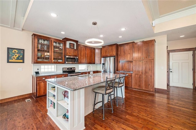 26793 W 100th Pl, Olathe, KS 66061 - kitchen with stainless steel appliances, brown cabinetry, open shelves, dark wood-style floors, and a breakfast bar