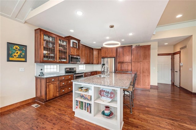 26793 W 100th Pl, Olathe, KS 66061 - kitchen with appliances with stainless steel finishes, open shelves, dark wood finished floors, a kitchen breakfast bar, and light stone countertops