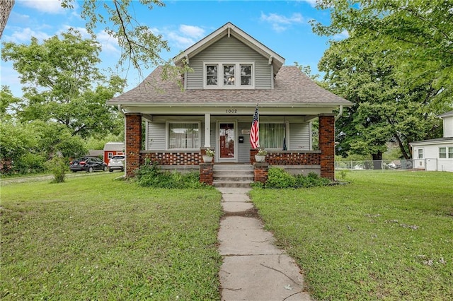 1002 S Olive St, Holden, MO 64040 - bungalow featuring a porch, a shingled roof, and brick siding