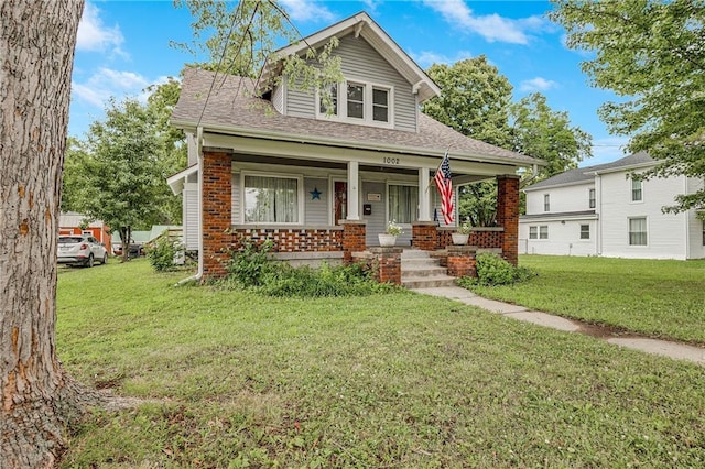 1002 S Olive St, Holden, MO 64040 - view of front of home with covered porch, a front lawn, brick siding, and a shingled roof