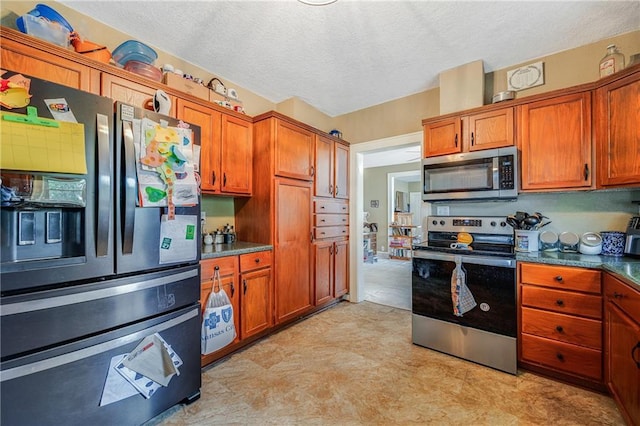 1002 S Olive St, Holden, MO 64040 - kitchen with stainless steel appliances, a textured ceiling, brown cabinetry, and light flooring