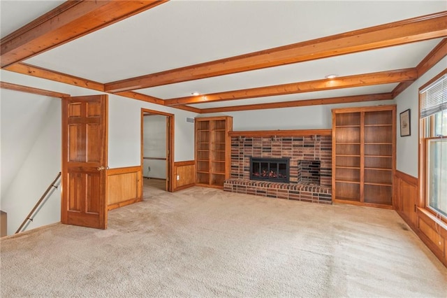320 SW Raven Ct, Lees Summit, MO 64081 - unfurnished living room featuring carpet floors, a wainscoted wall, beamed ceiling, a brick fireplace, and wooden walls
