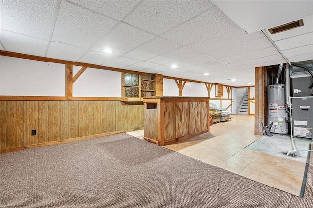 602 N Westview Dr, Richmond, MO 64085 - finished below grade area featuring gas water heater, stairs, heating unit, a paneled ceiling, and wood walls