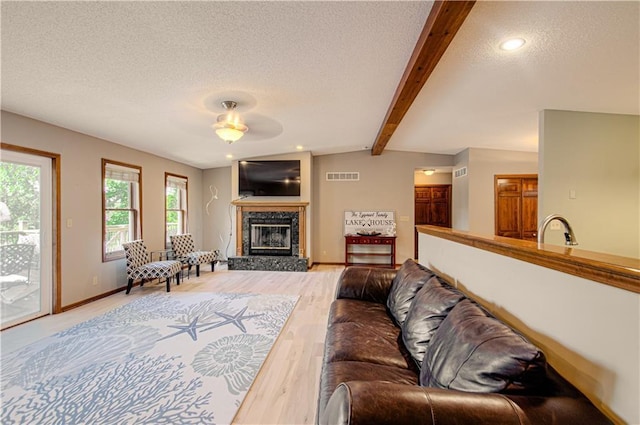 106 Timber Valley Dr, Linn Valley, KS 66040 - living area with a textured ceiling, beam ceiling, wood finished floors, a glass covered fireplace, and ceiling fan