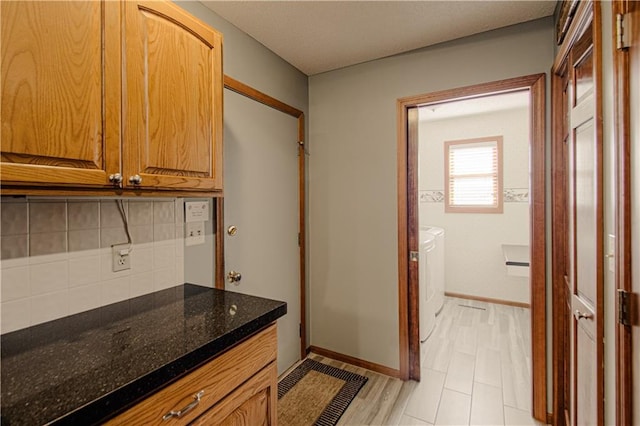 106 Timber Valley Dr, Linn Valley, KS 66040 - kitchen with washer and dryer, decorative backsplash, dark stone countertops, and brown cabinetry